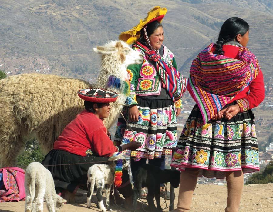 Colourfully dressed women in Peru with a lama and babies